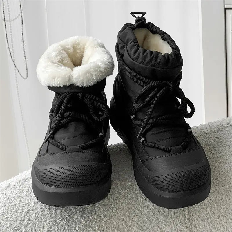 Pair of black winter boots with white fur lining on a light gray surface.