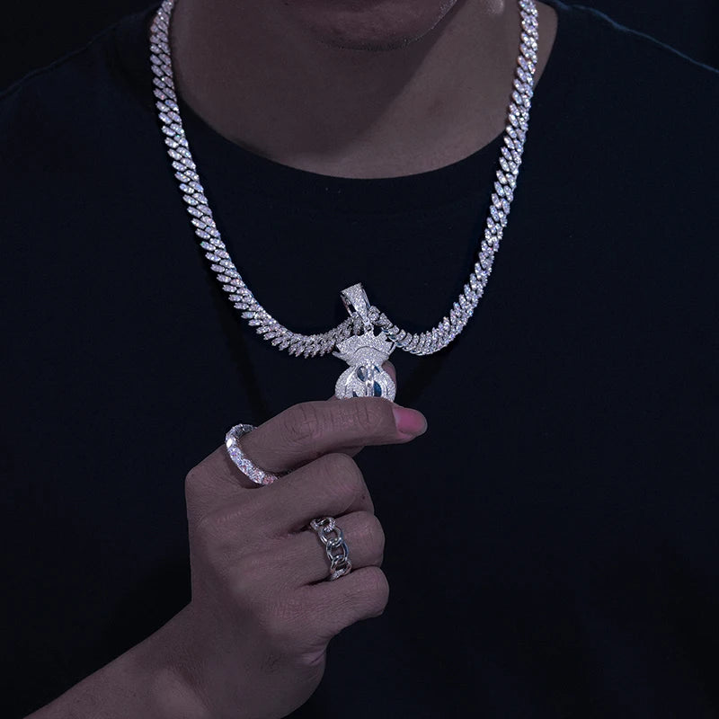 Person wearing a large diamond-encrusted necklace and rings on a black background