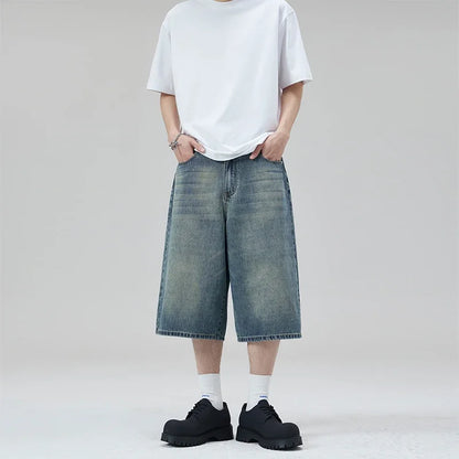 Person wearing a white t-shirt, blue denim shorts, and black shoes on a plain background