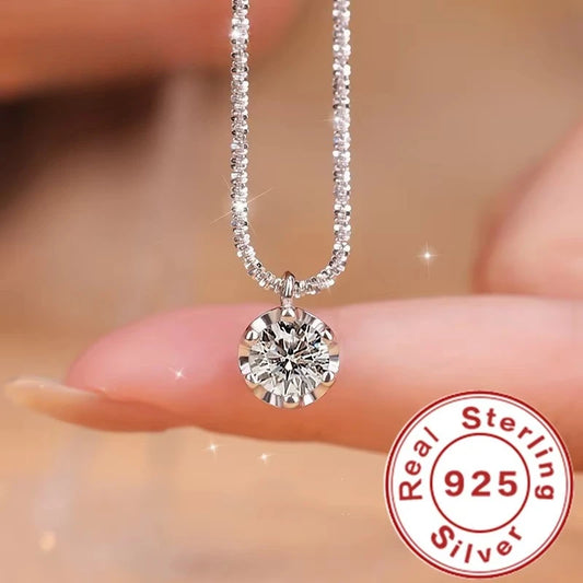 Silver necklace with a diamond pendant held by hands, featuring a 'Real Sterling 925' stamp.