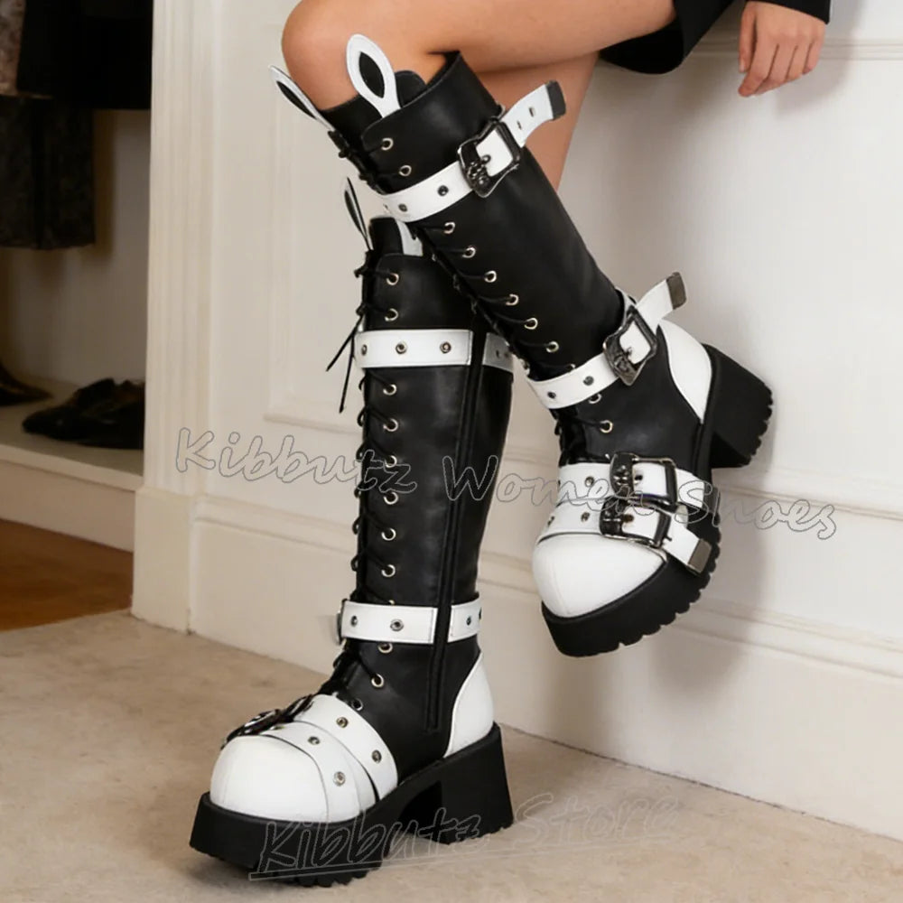 Black and white knee-high boots with buckles worn by a person indoors.