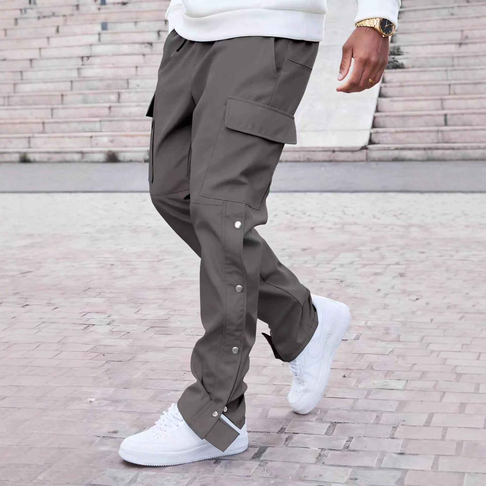Person wearing gray cargo pants and white sneakers on a brick pavement.