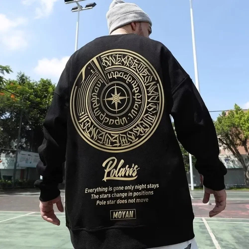 Person wearing a black sweatshirt with gold designs and text on a basketball court