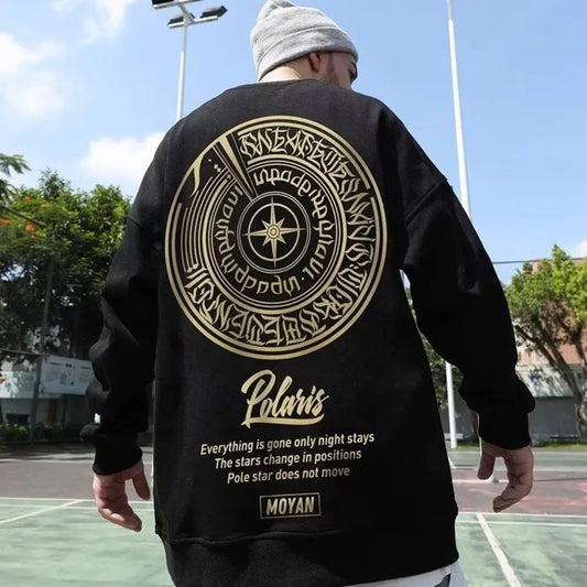 Person wearing a black sweatshirt with gold designs and text on a basketball court