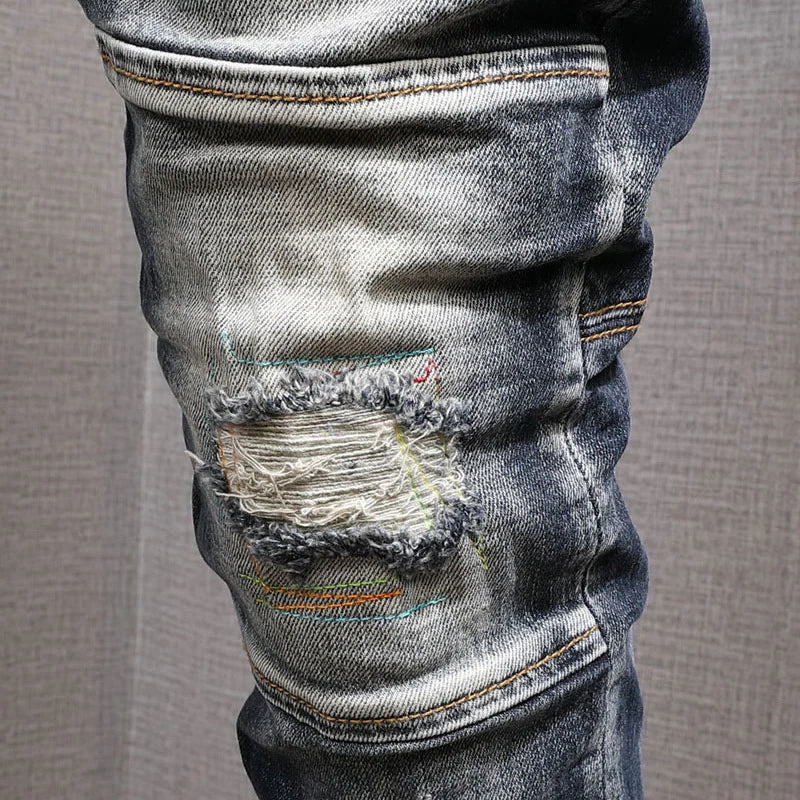 Close-up of distressed denim jeans on a neutral background