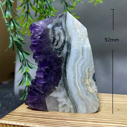 Amethyst crystal on a wooden surface with a plant in the background