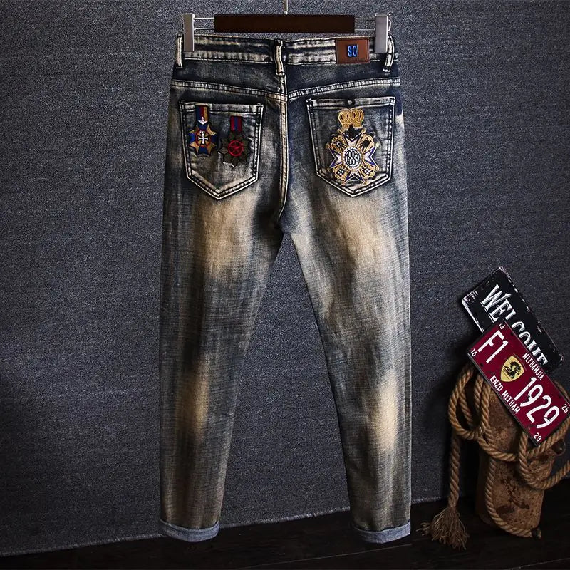 Denim jeans with embroidered patches on a textured gray background