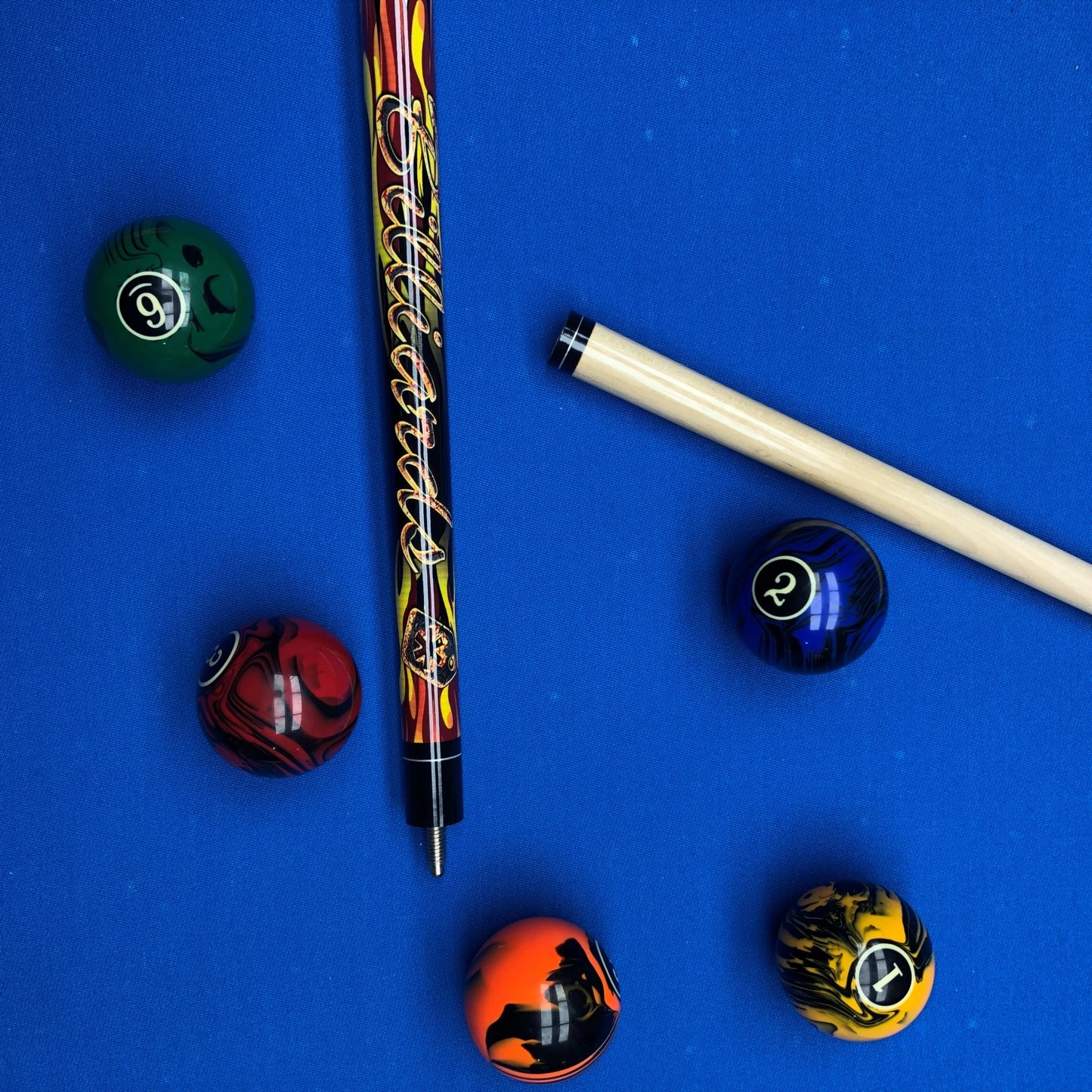 Pool balls and a cue on a blue felt background