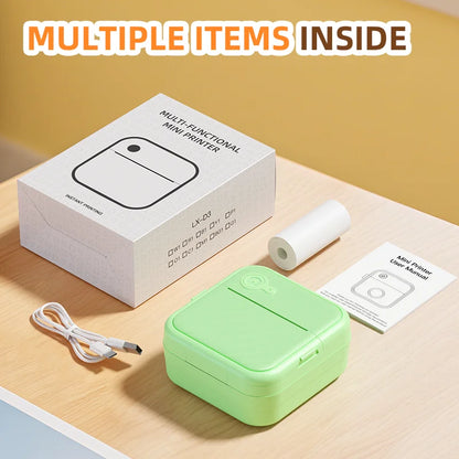 Green multi-functional mini printer with packaging, cable, and paper on a wooden surface.