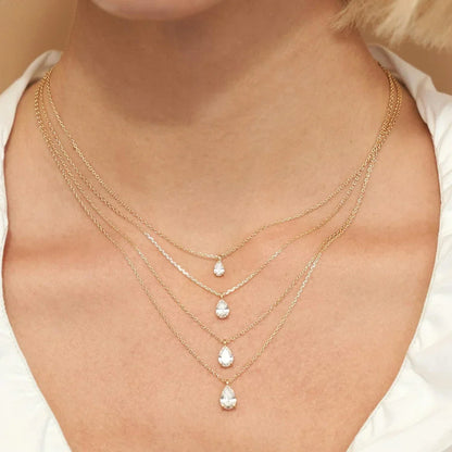 Close-up of a person wearing multiple gold necklaces with teardrop-shaped pendants.