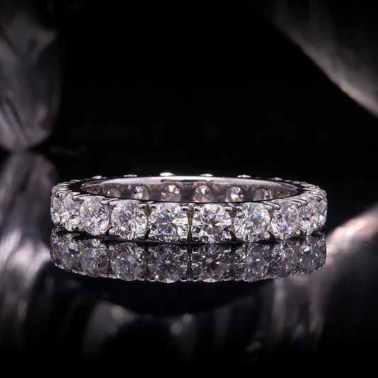 Diamond eternity ring on a reflective surface with a dark background