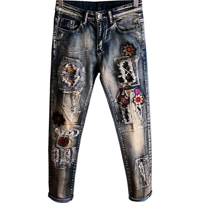 Distressed jeans with patches and embellishments on a white background
