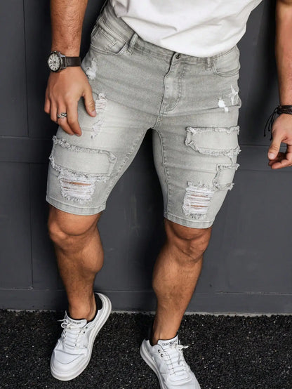 Person wearing light gray distressed denim shorts with white sneakers against a dark background