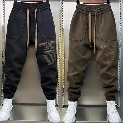 Black and brown jogger pants with 'HEDONIST' text on a metallic background