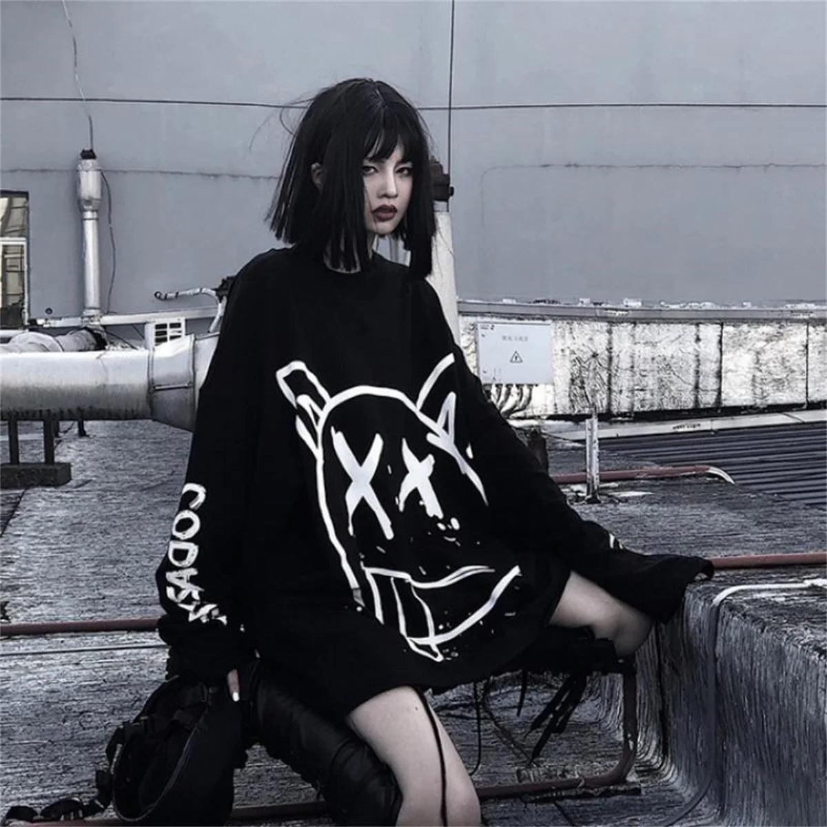 Person wearing a black sweater with white graphics in an urban setting