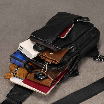Black crossbody bag with various compartments and items on a gray surface