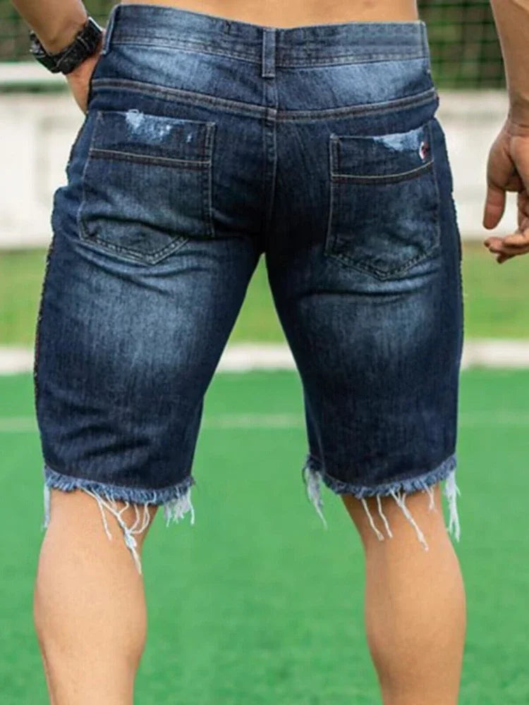 Person wearing blue denim shorts on a green outdoor background
