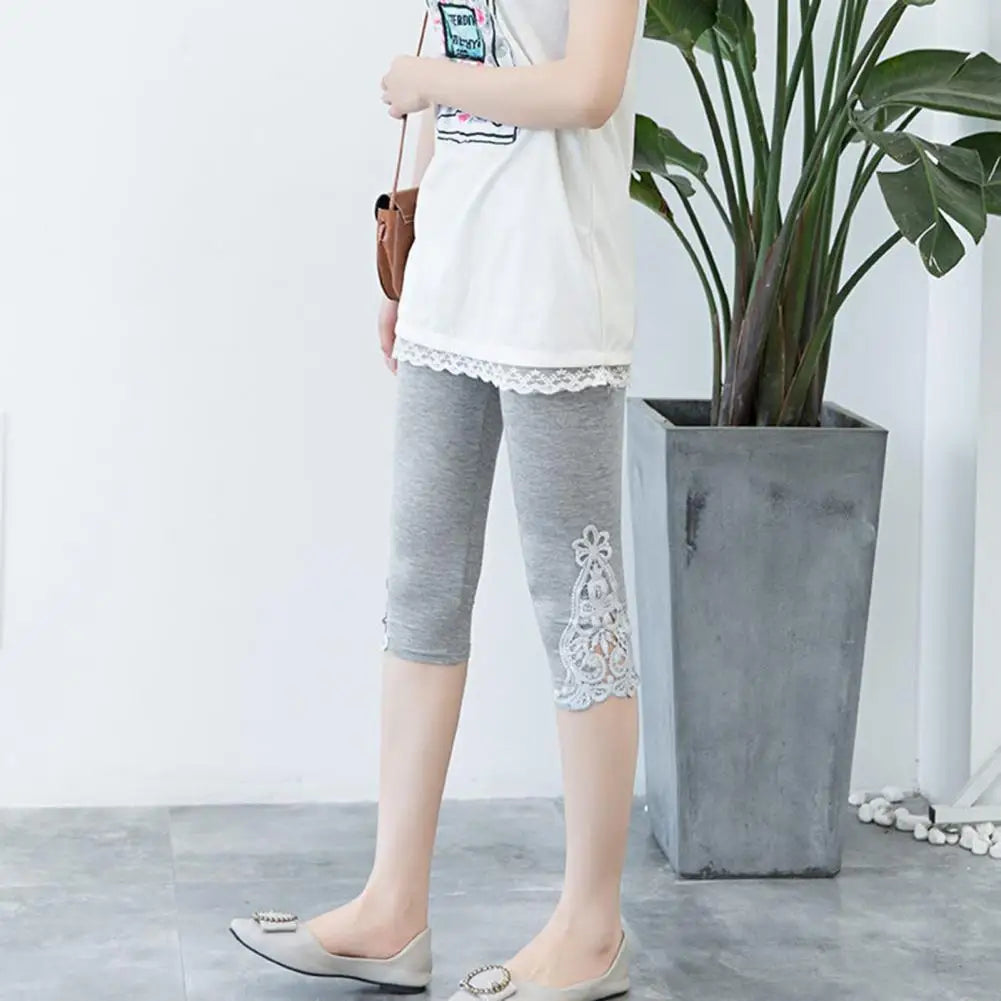 Person wearing gray capri pants with lace details in a minimal indoor setting.