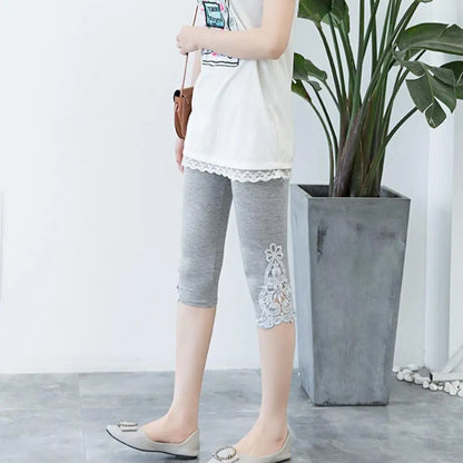 Person wearing gray capri pants with lace details in a minimal indoor setting.