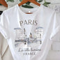 White t-shirt with Paris-themed design and text on a hanger.