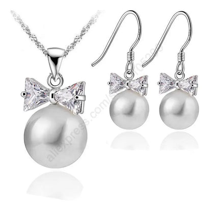 Pearl necklace and earrings set with bow and crystal details on a white background