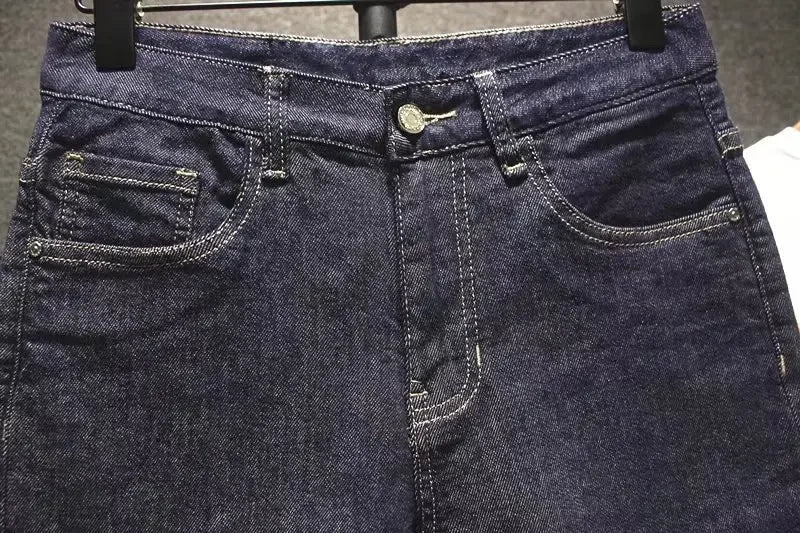 Close-up of dark blue jeans with a focus on the waistband and pockets.