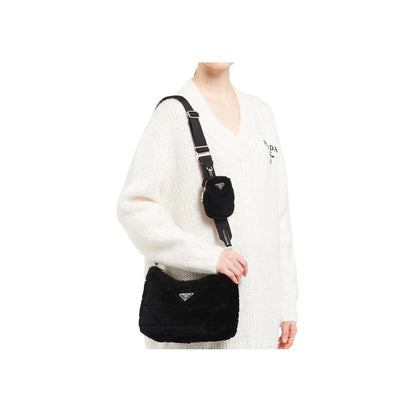 Person wearing a white sweater with a black Prada handbag on a white background
