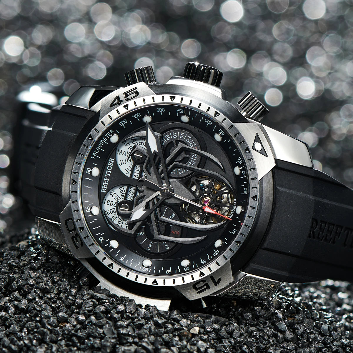 Black and silver watch with detailed face on a textured surface