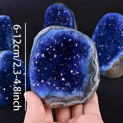 Blue crystal geode held in hand with size measurement on a black background