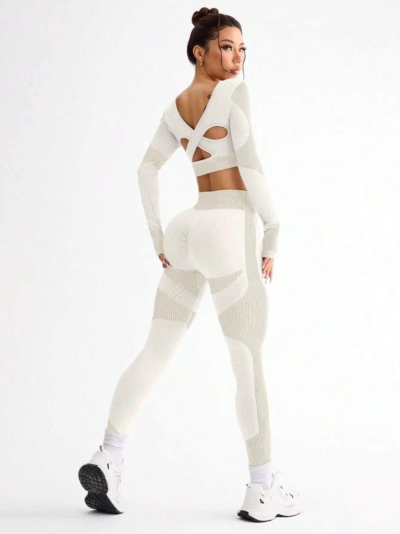 Woman wearing a white knit outfit with cut-out design on a white background