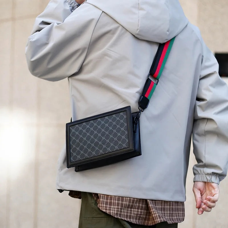 Person wearing a light gray jacket with a black rectangular bag on a neutral background