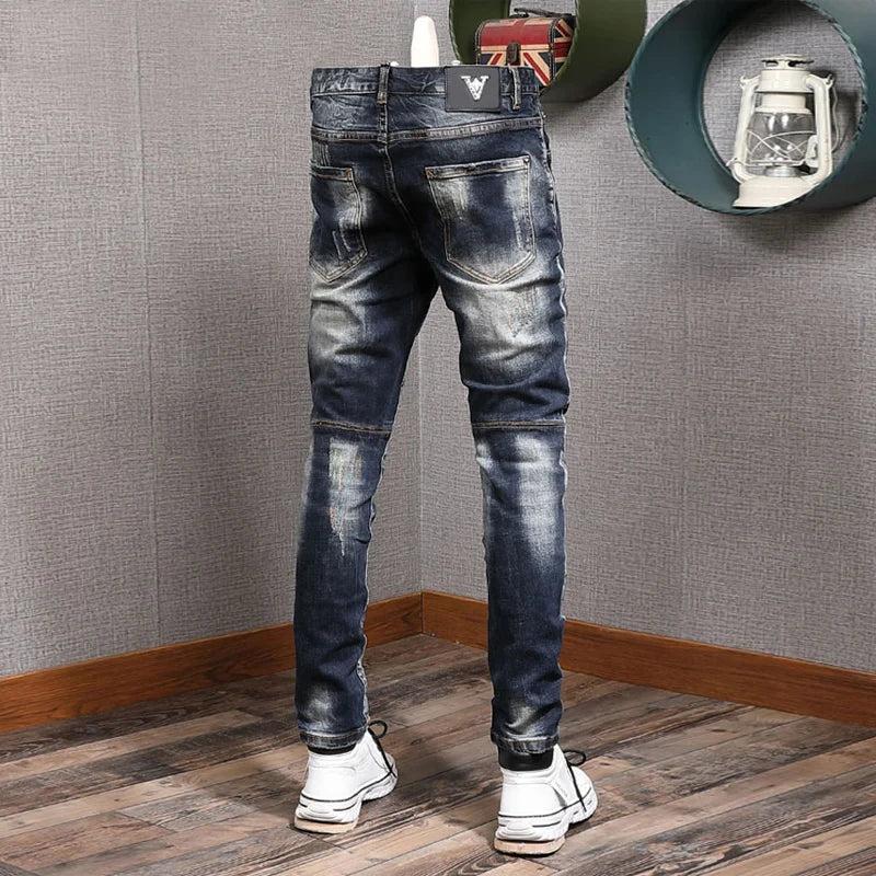 Person wearing distressed blue jeans in a room with gray walls and wooden floor.