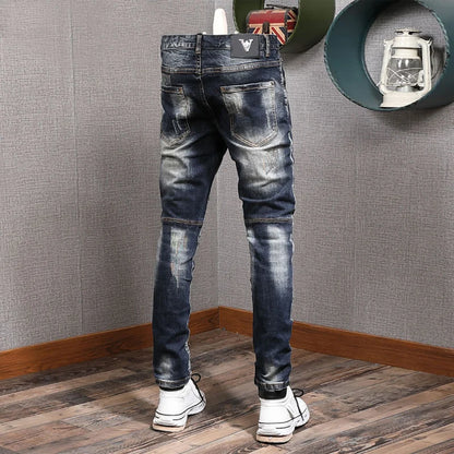 Person wearing distressed blue jeans in a room with gray walls and wooden floor.