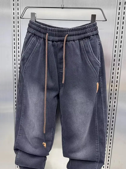 Dark gray jogger pants with a drawstring on a hanger against a neutral background