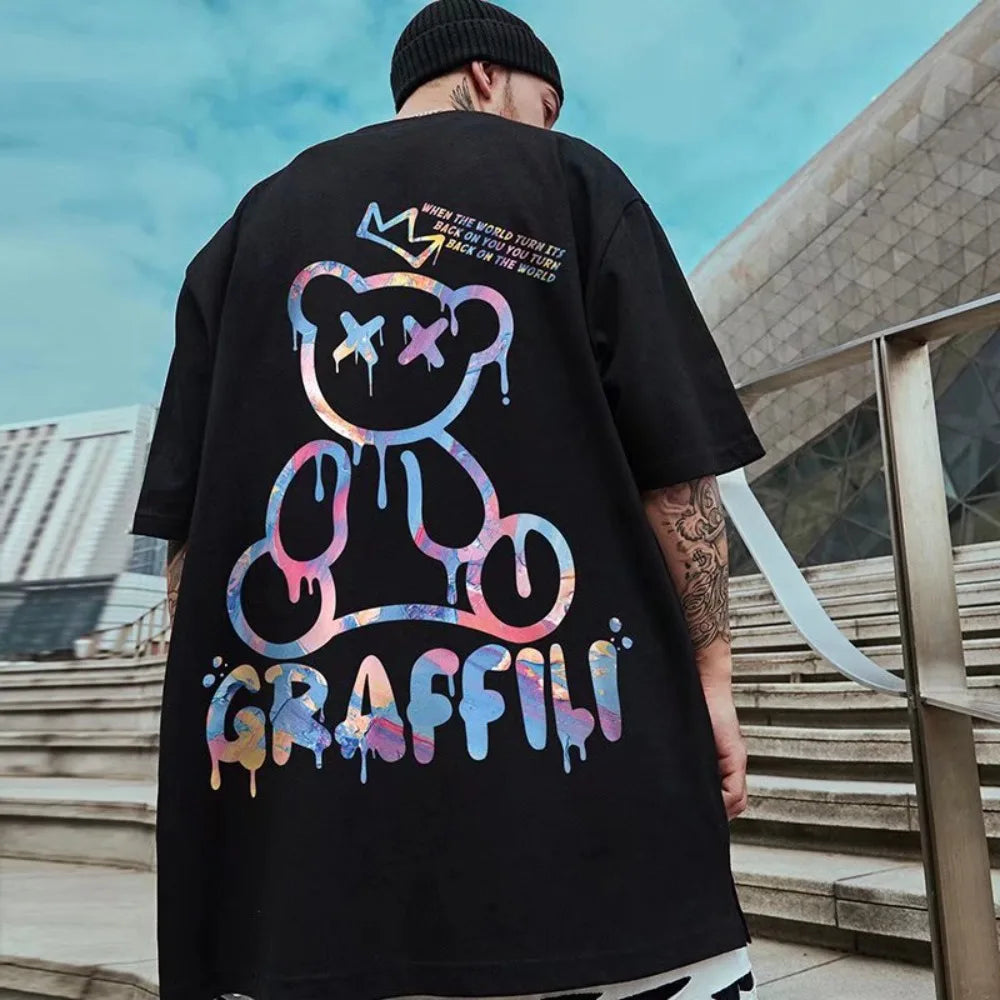 Person wearing a black t-shirt with colorful bear graphic and 'Graffiti' text outdoors.