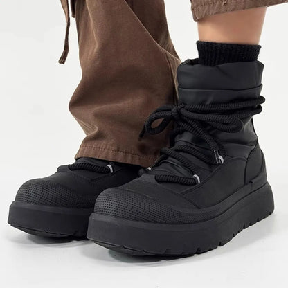 Black platform boots worn with brown pants on a white background