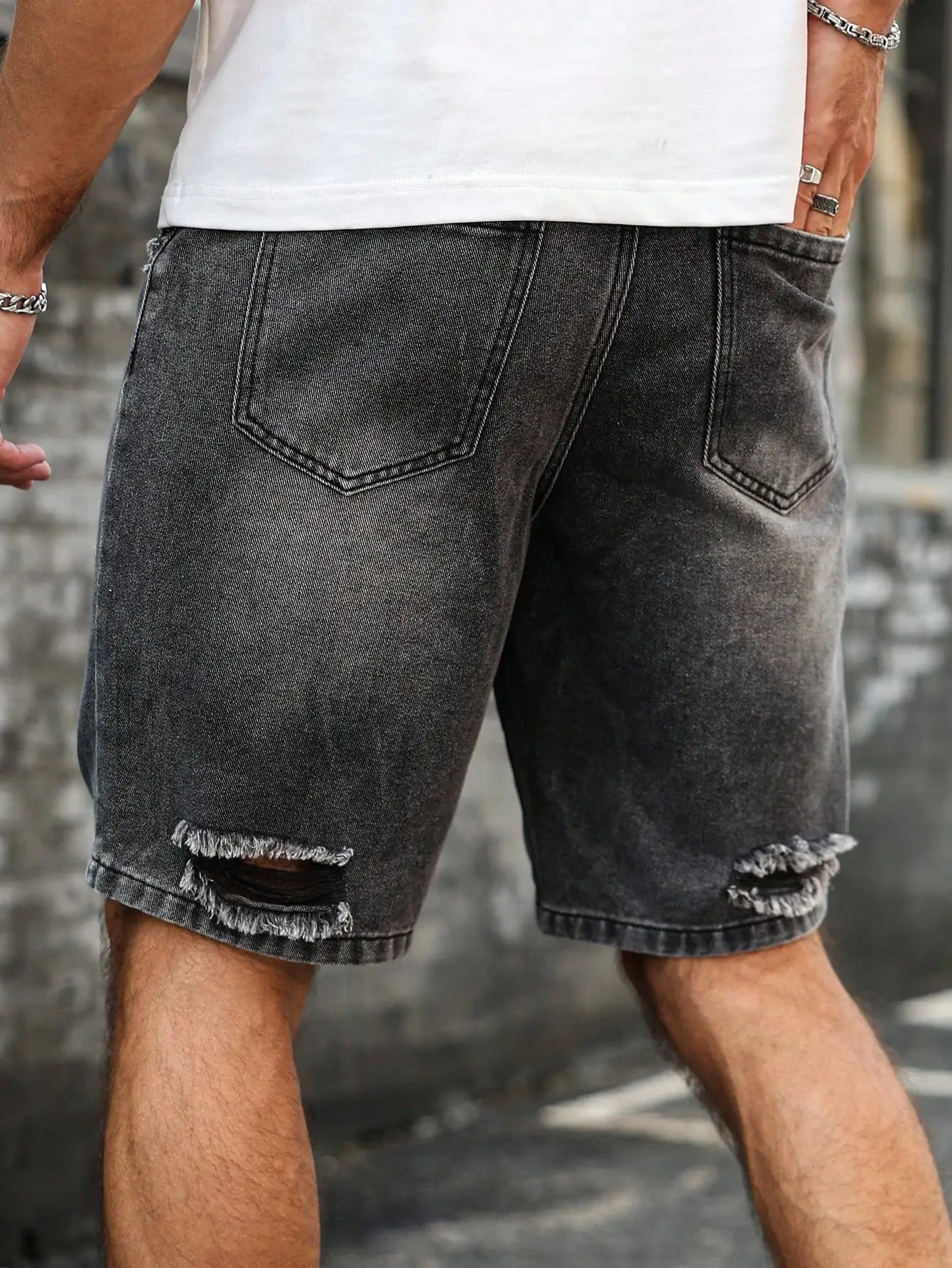 Black distressed denim shorts worn by a person against a blurred background