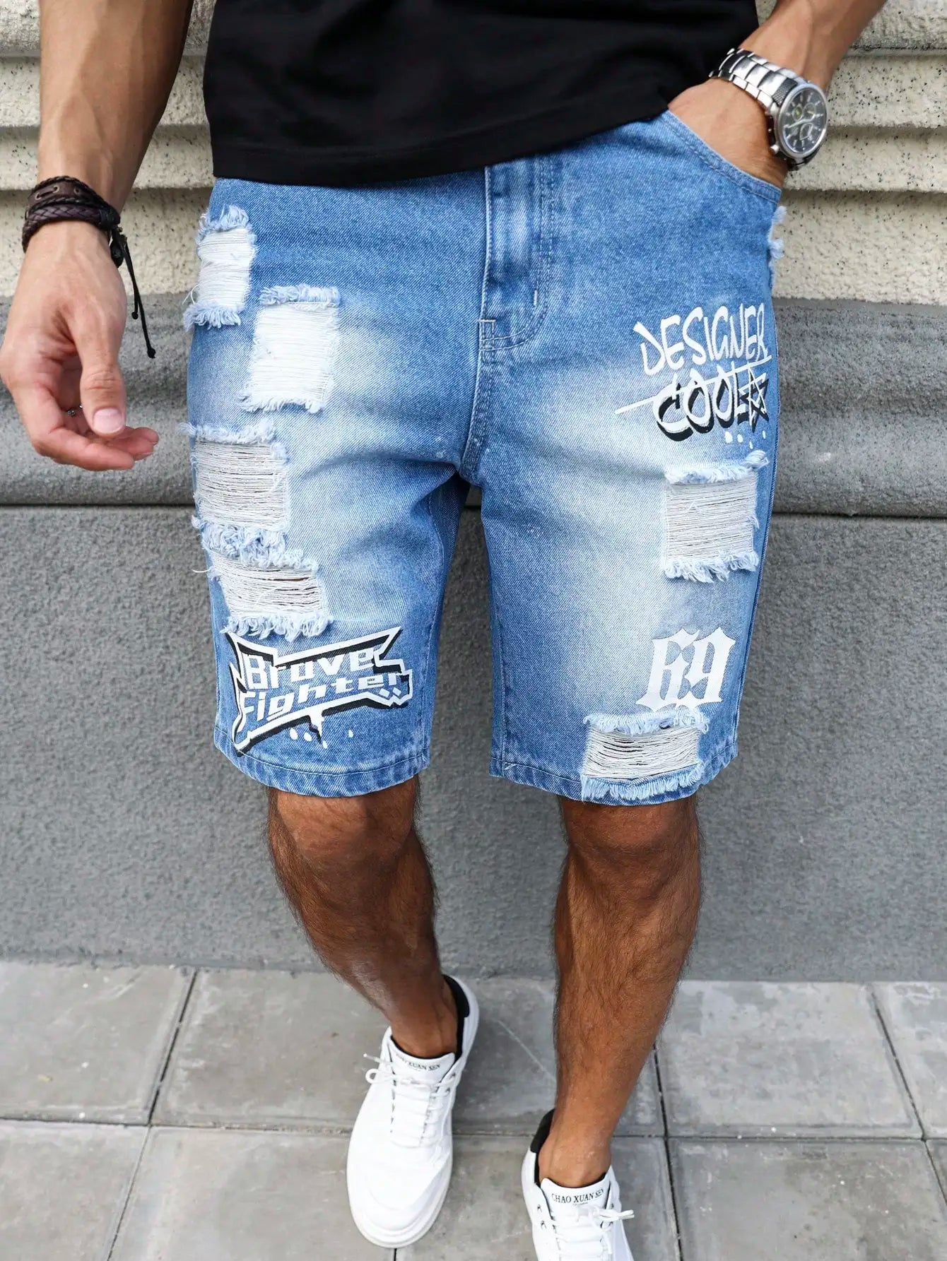 Person wearing distressed blue denim shorts with text design on a gray concrete background