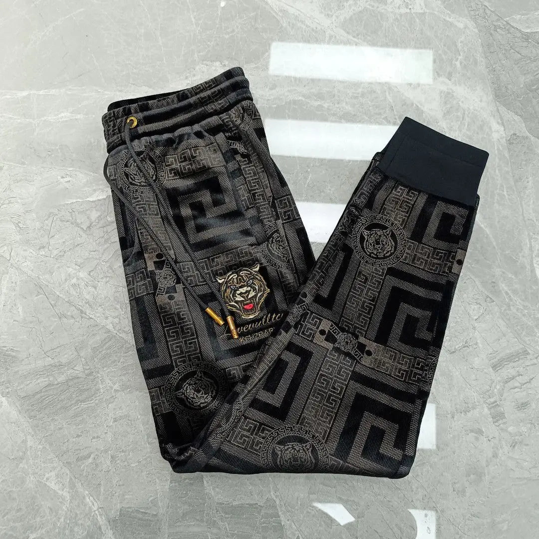 Black patterned pants with a tiger emblem on a gray textured background