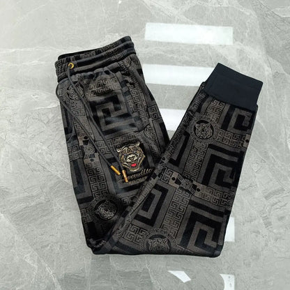Black patterned pants with a tiger emblem on a gray textured background