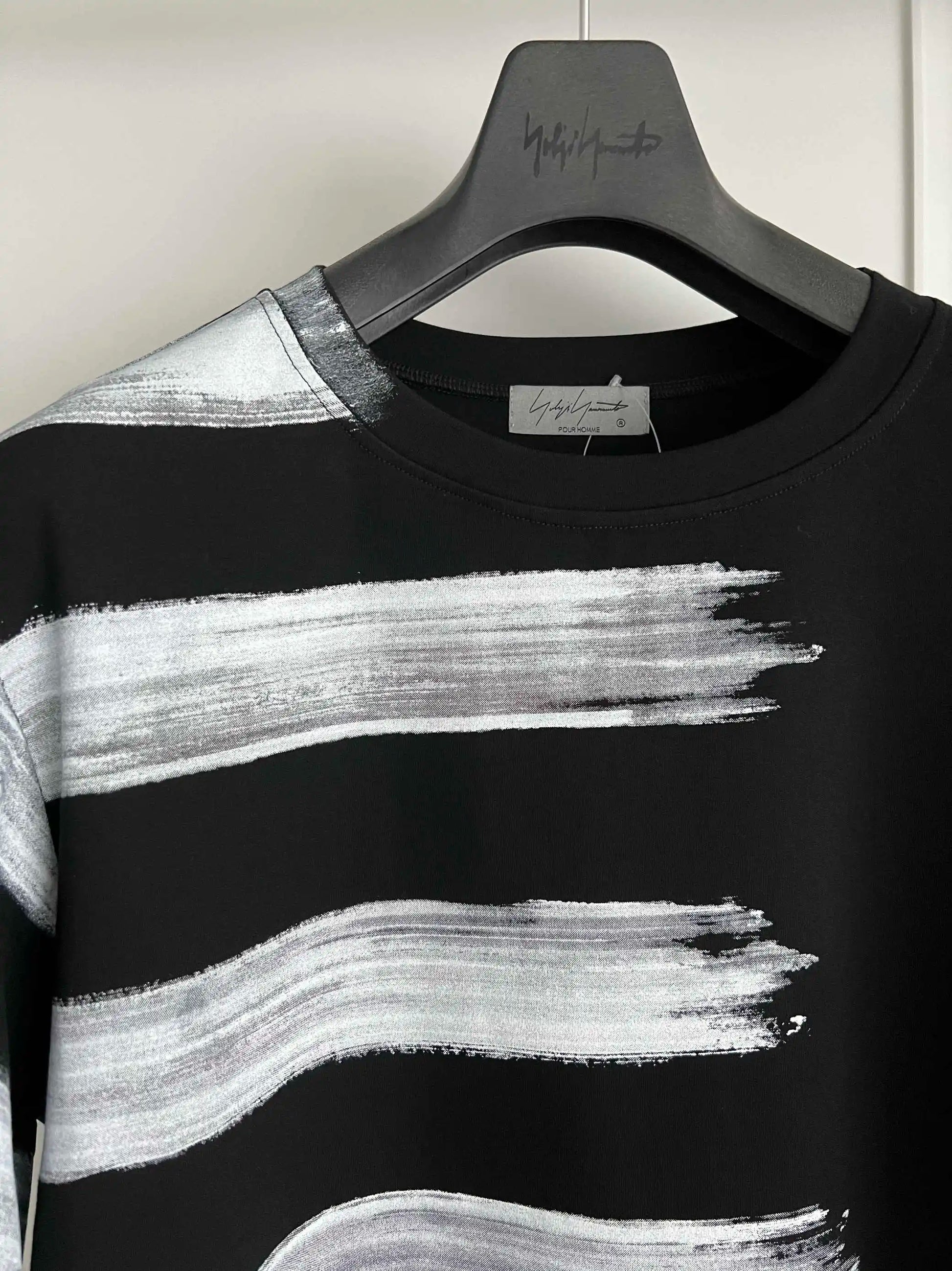 Black and white striped shirt on a hanger with a visible brand label.