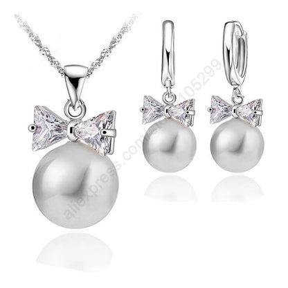 Pearl necklace and earrings with bow accents on a white background
