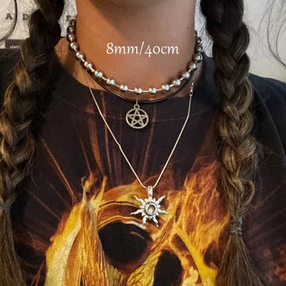 Necklaces with pentacle and sun pendant on a person wearing a shirt with a dragon design.