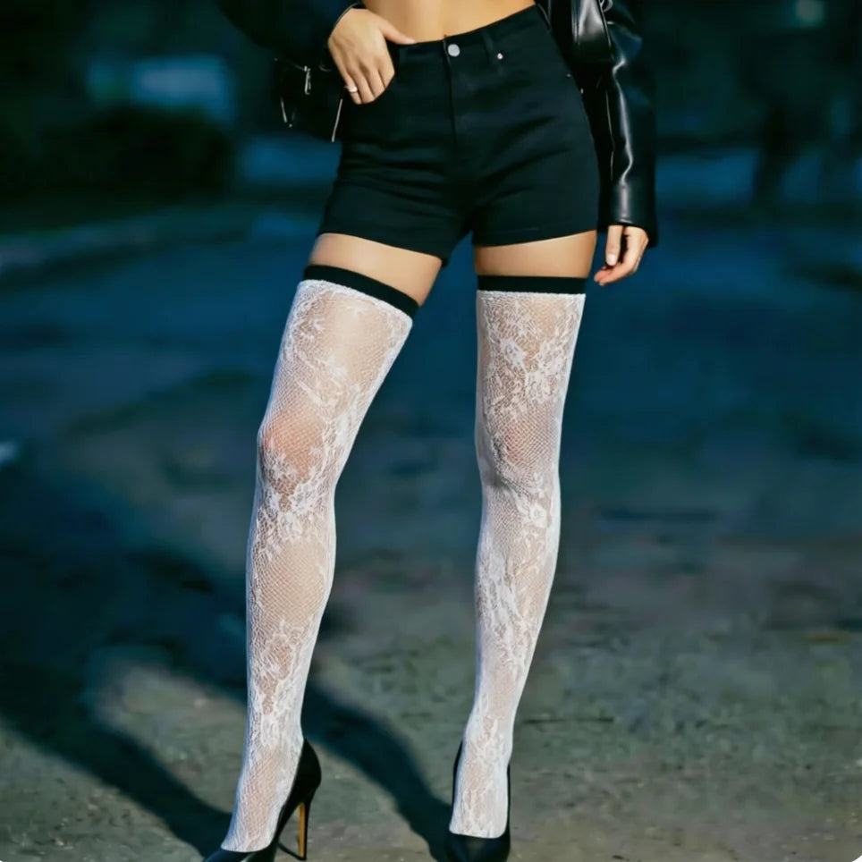 Person wearing white lace thigh-high stockings with black shorts and high heels on a blurred background