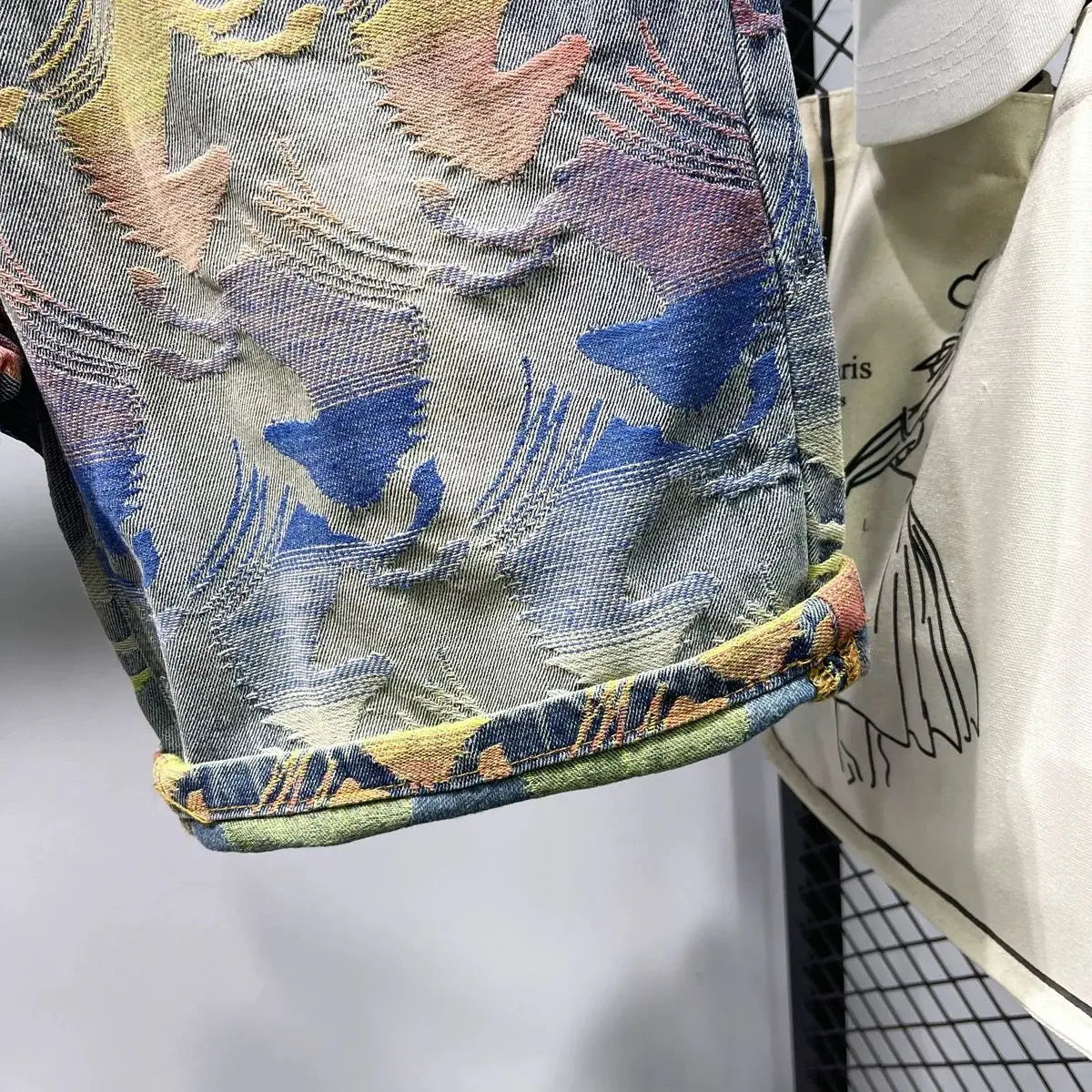 Close-up of a denim jacket with colorful embroidery on a white background