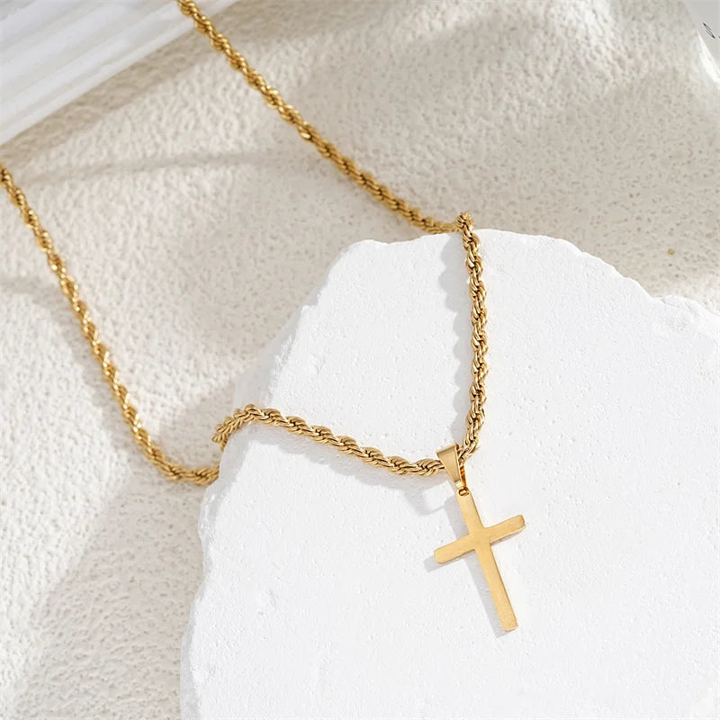 Gold necklace with a cross pendant on a textured white surface