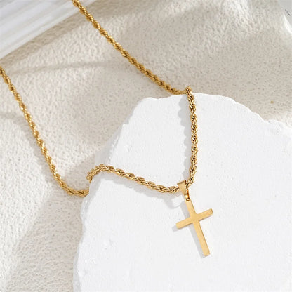 Gold necklace with a cross pendant on a textured white surface