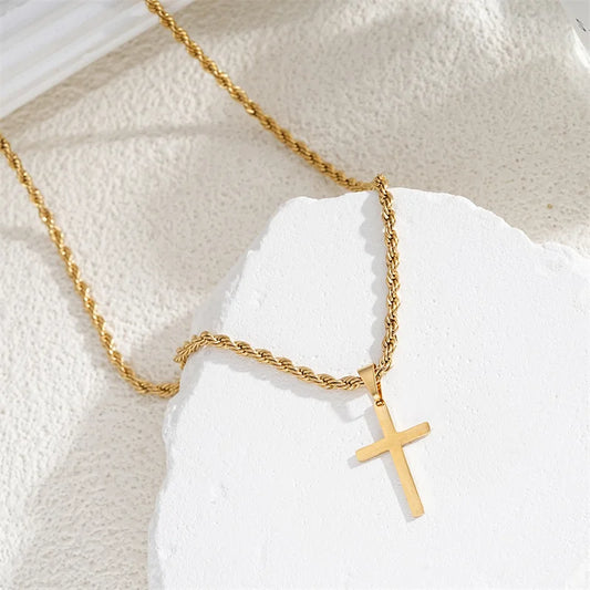 Gold necklace with a cross pendant on a textured white surface