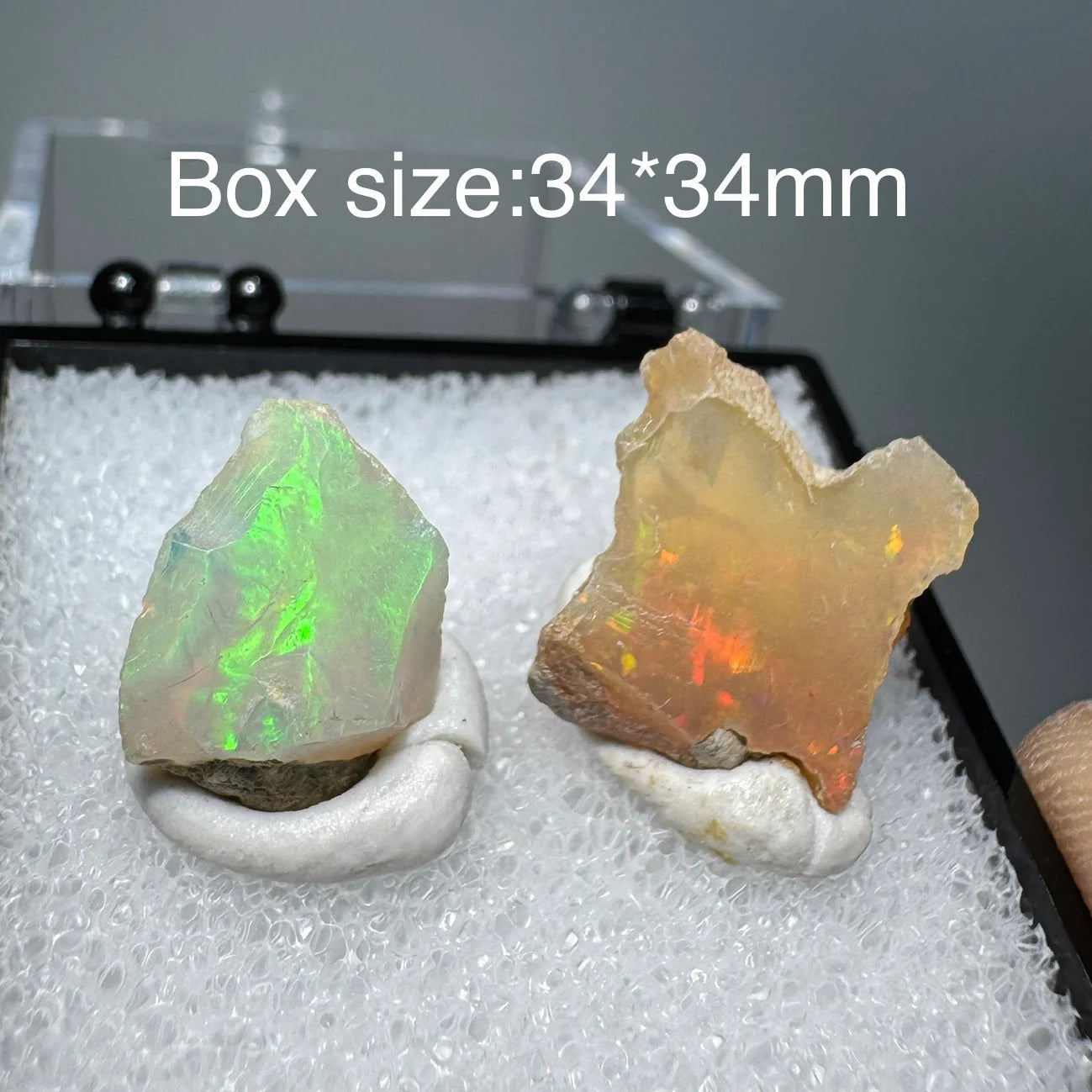 Two pieces of opal stone on a white cushion with a box size label in the background.