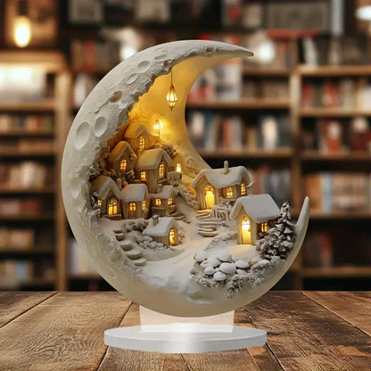 Decorative moon-shaped lamp with a village scene on a wooden table in a bookshelf setting